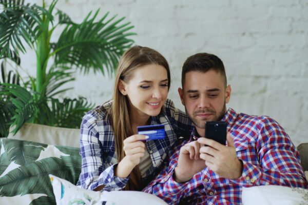 Couple happily shopping online with credit card and phone.