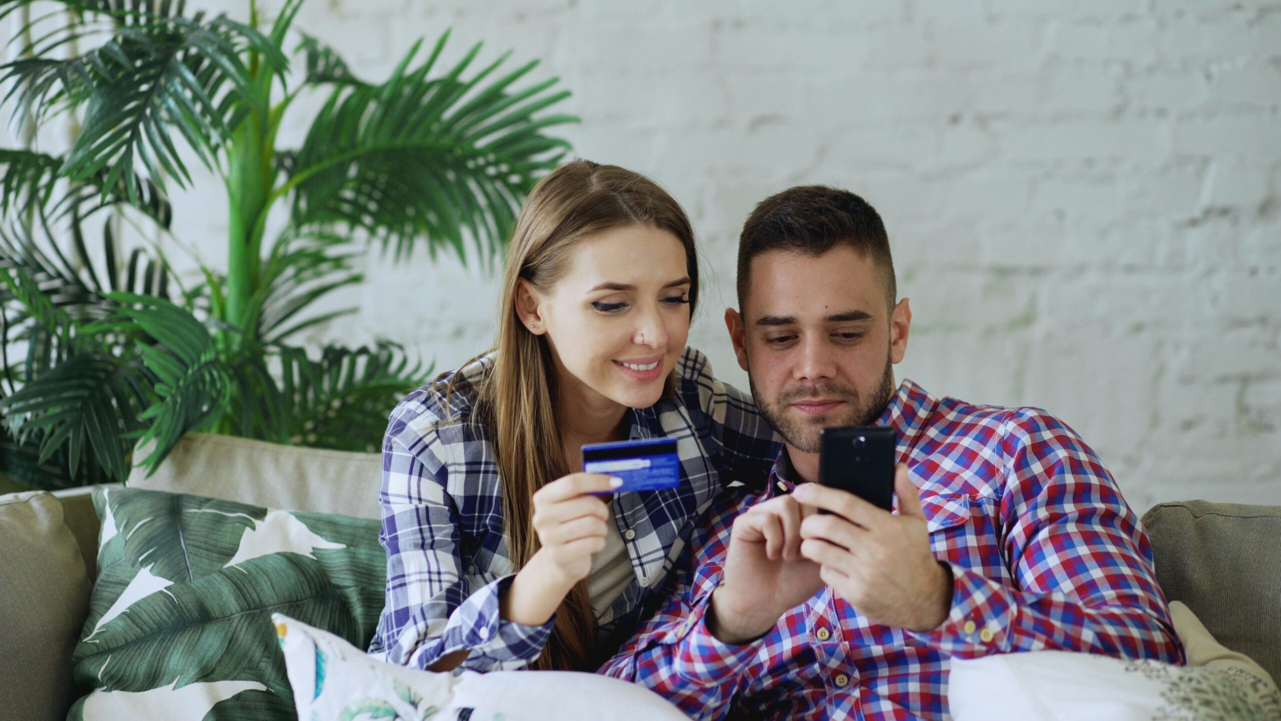 Couple happily shopping online with credit card and phone.