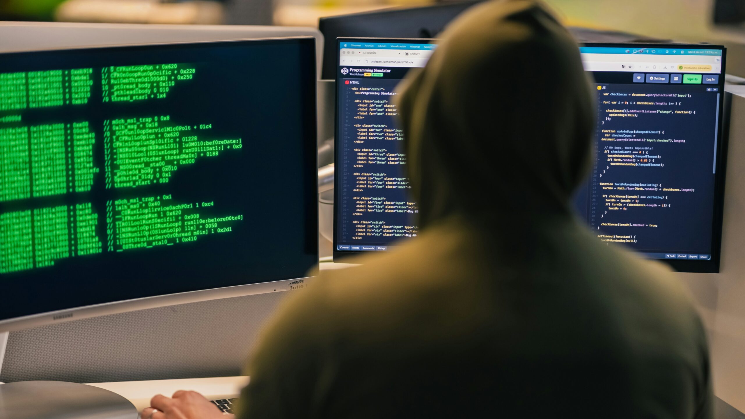 Hacker in hoodie working on multiple computer screens