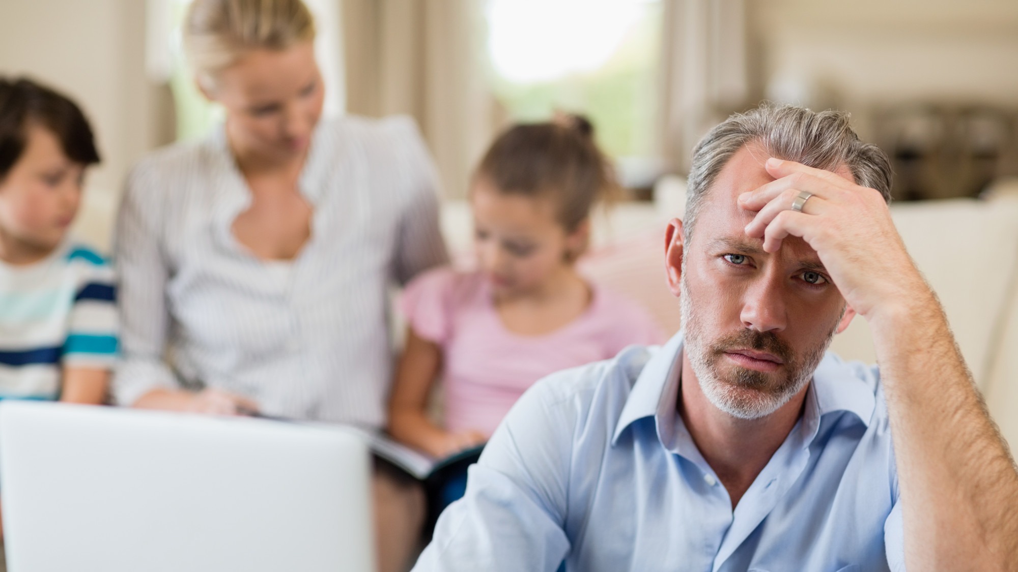 Tense man with hand on forehead sitting in living room