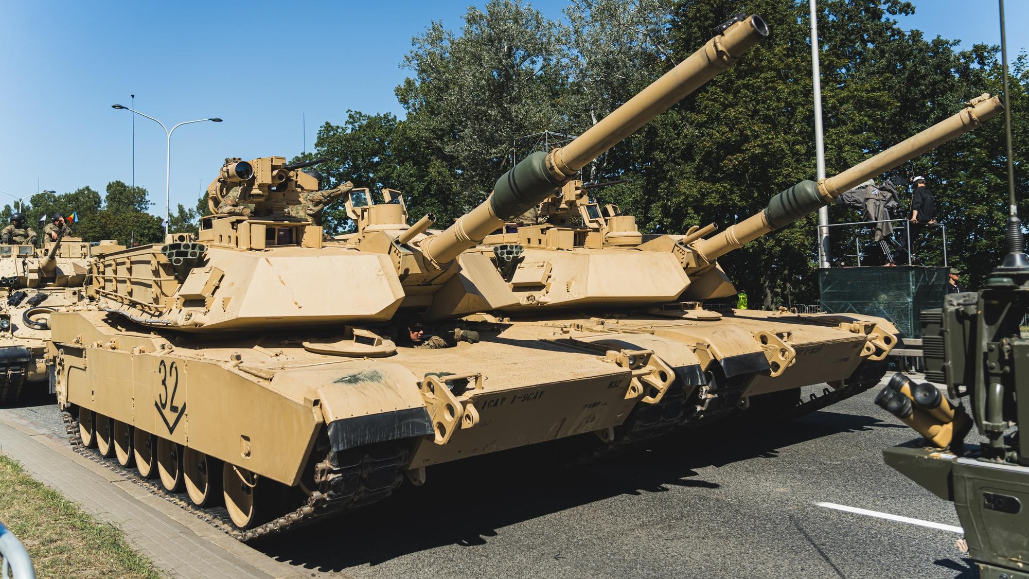 Focus on two m abrams main battle tanks driving in a column during an openair military parade in