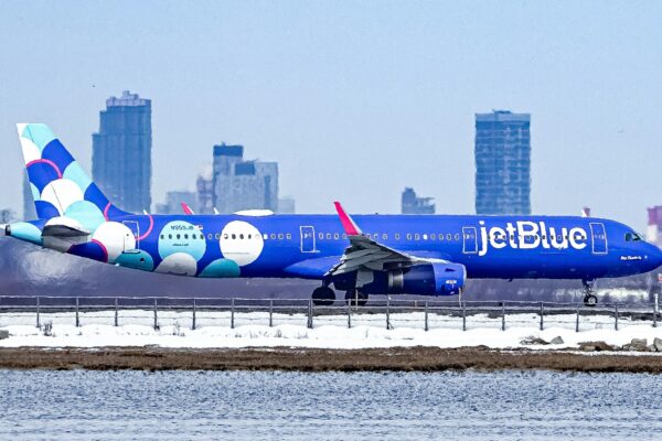 A blue jetblue airplane lands with city skyline background