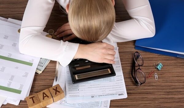 Tired businesswoman of calculating expenses at desk in office
