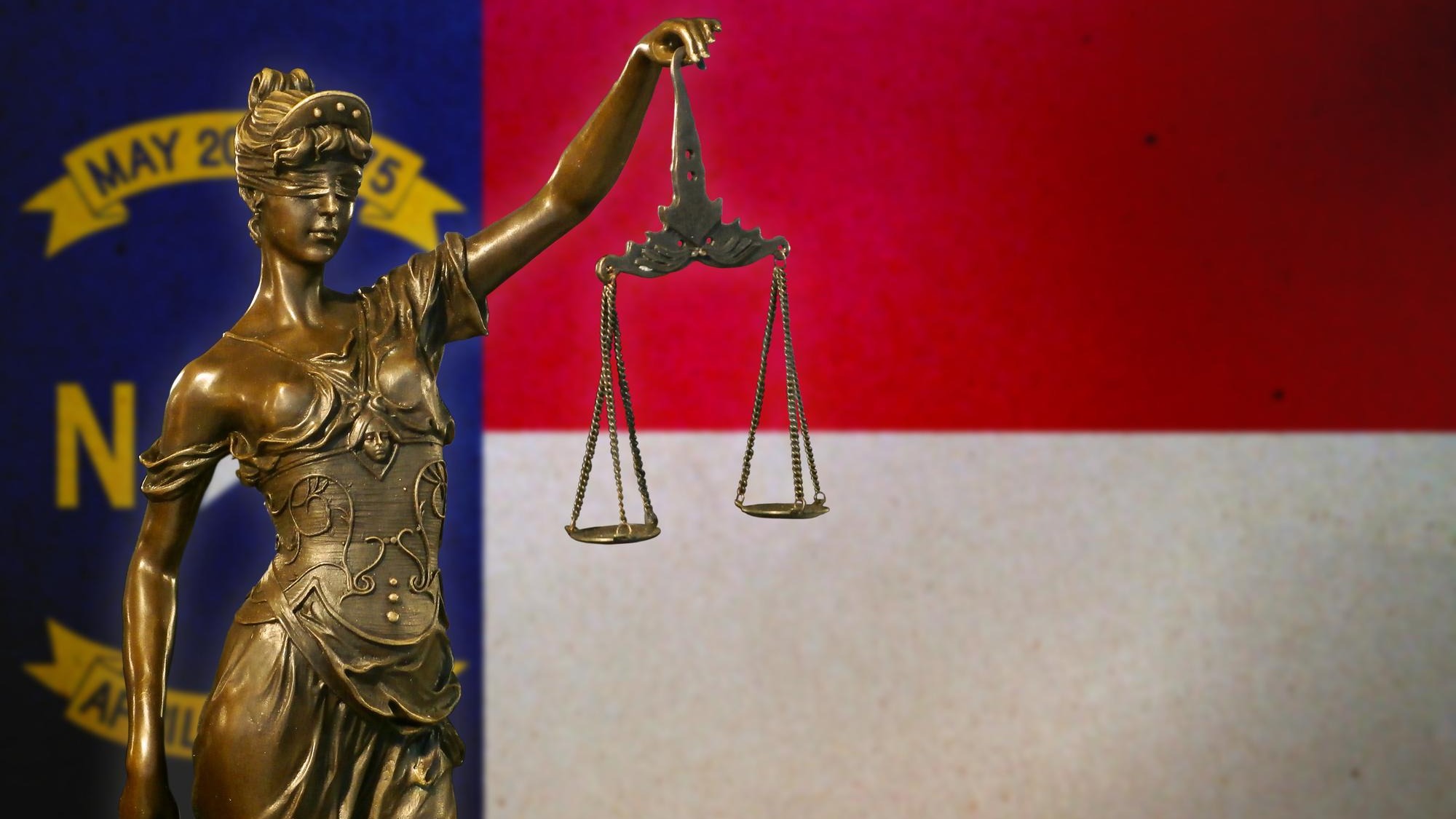 Lady Justice before a flag of North Carolina