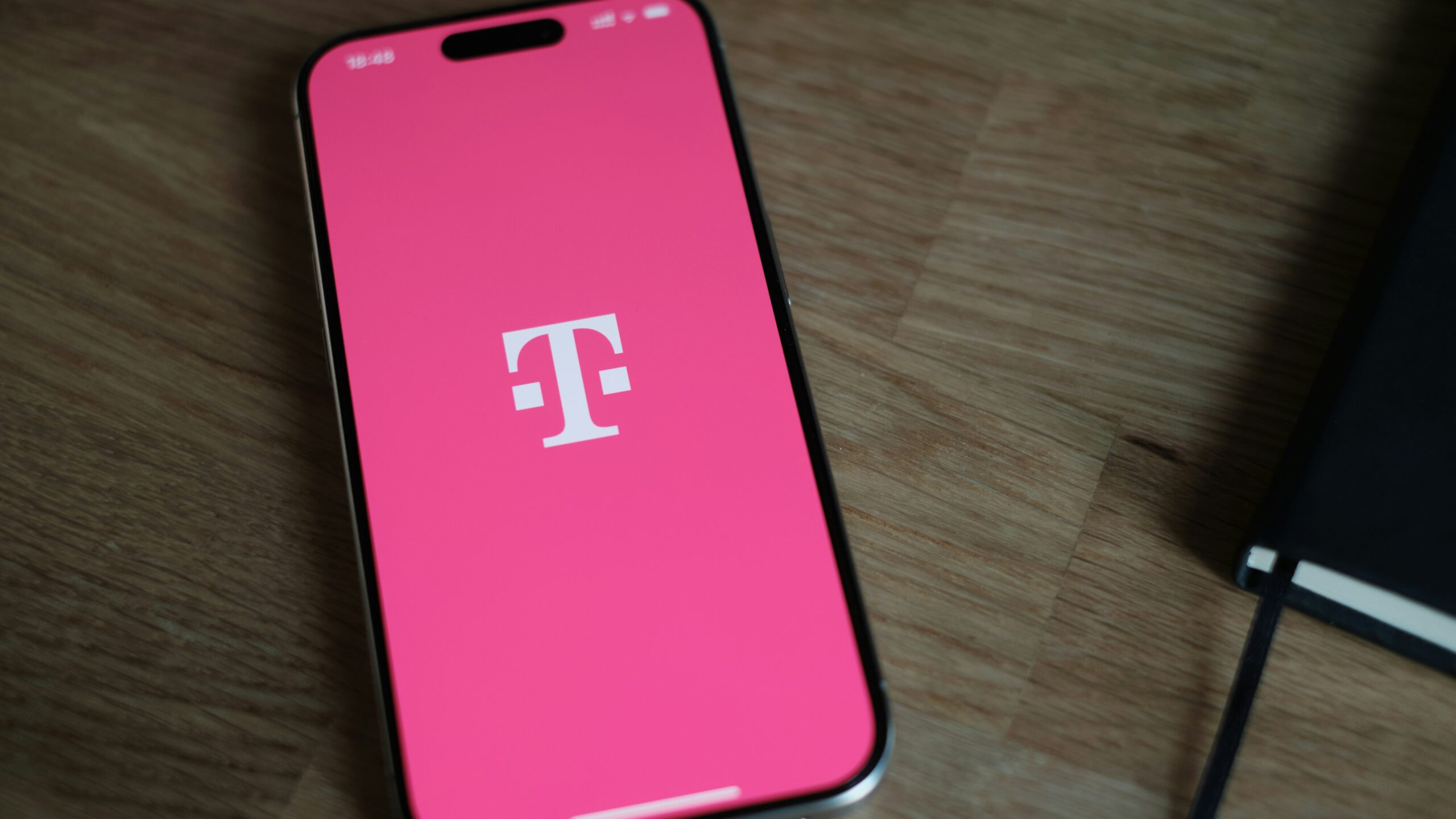 A pink phone sitting on top of a wooden table