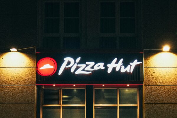 a man walking past a pizza hut at night