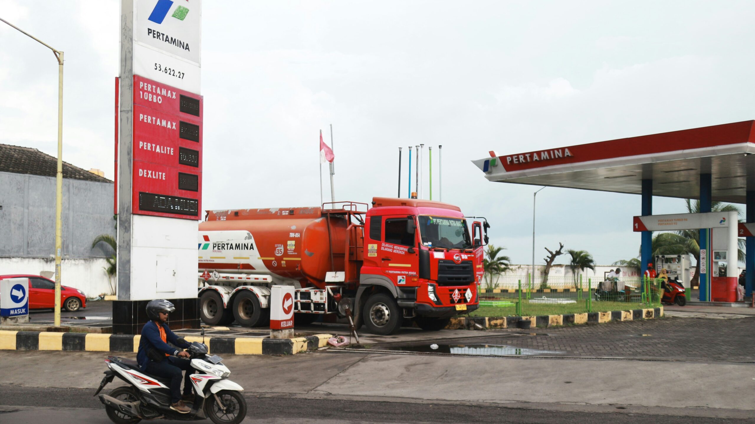 A red tanker truck at a gas station.