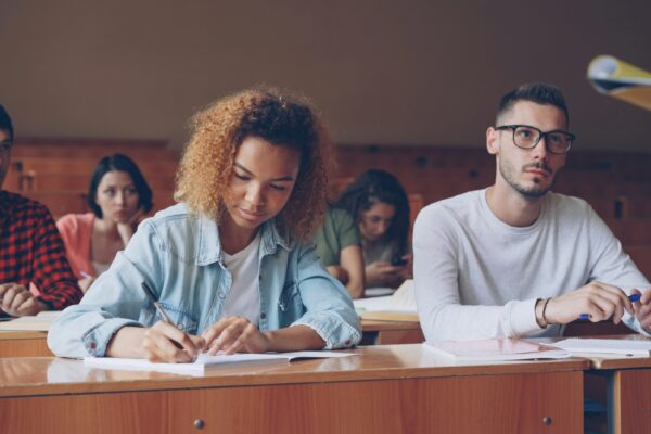 Students attentively taking notes in a lecture hall.