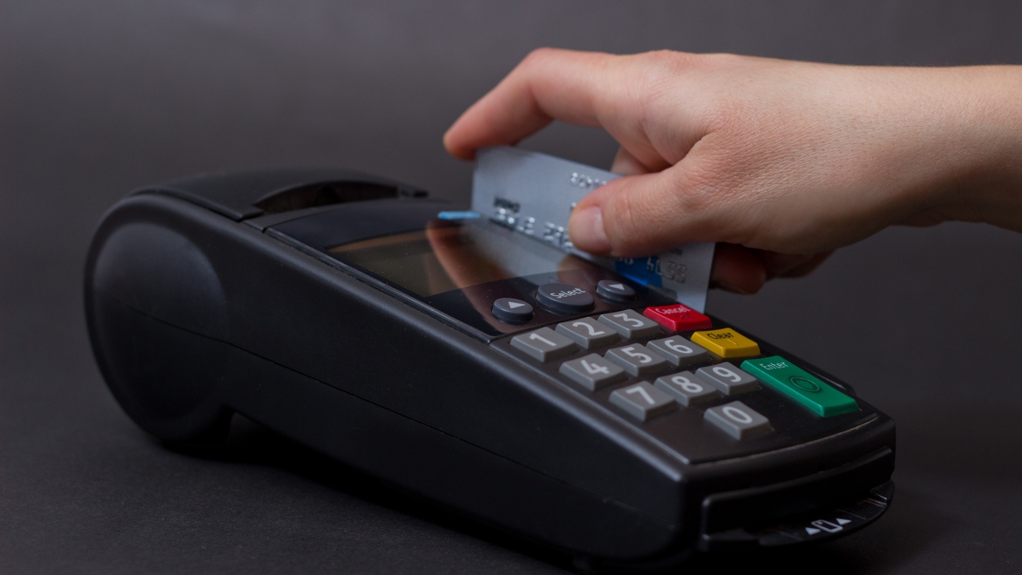 Hand Swiping Credit Card In Store. Female hands with credit card and bank terminal. Color image of a POS and credit cards.