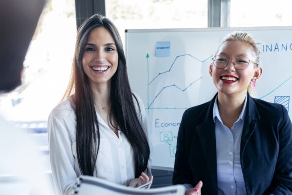 Shot of two elegant young businesswomen smiling and looking to her colleague on meeting in the coworking space.
