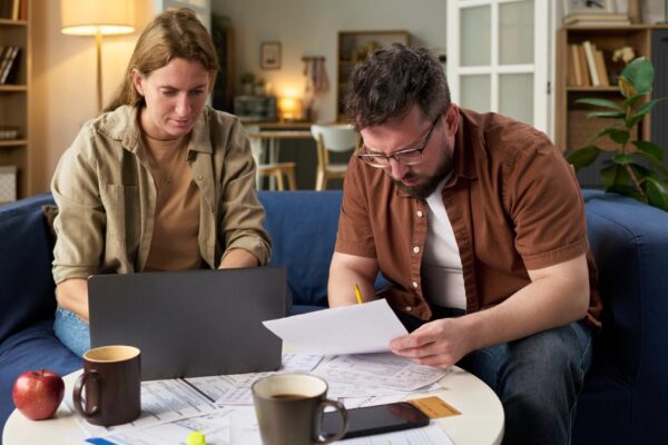 Caucasian young adult man and woman reviewing financial papers while paying taxes