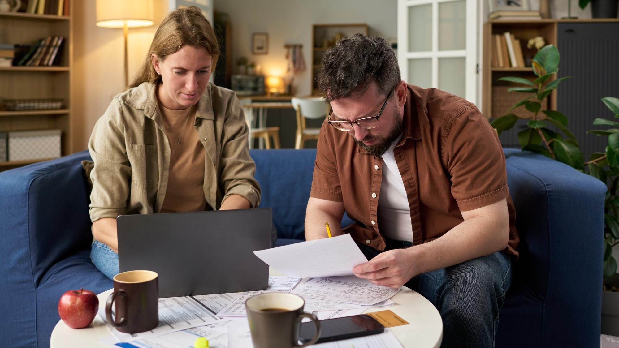 Caucasian young adult man and woman reviewing financial papers while paying taxes