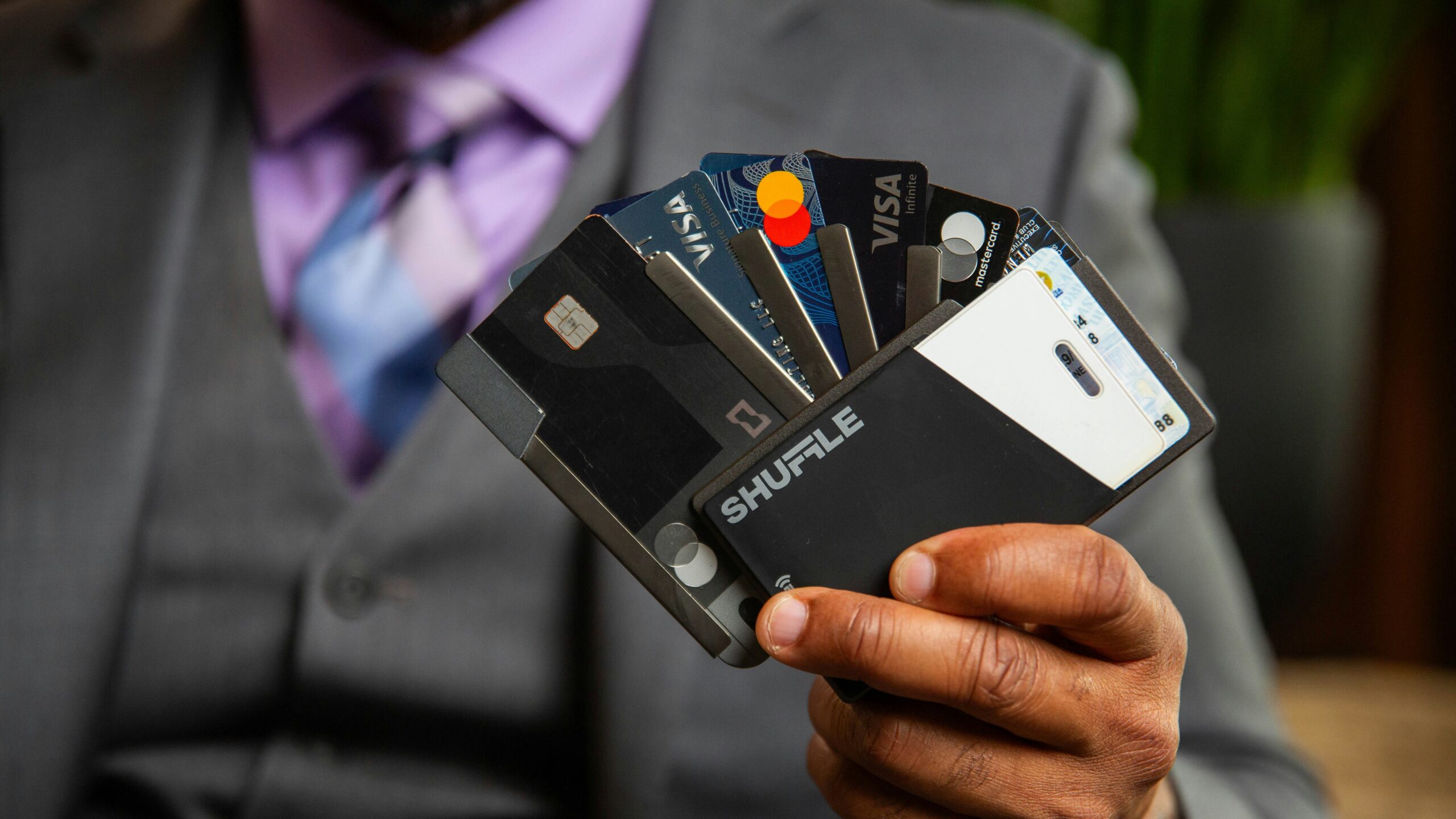 a man in a suit holding four credit cards