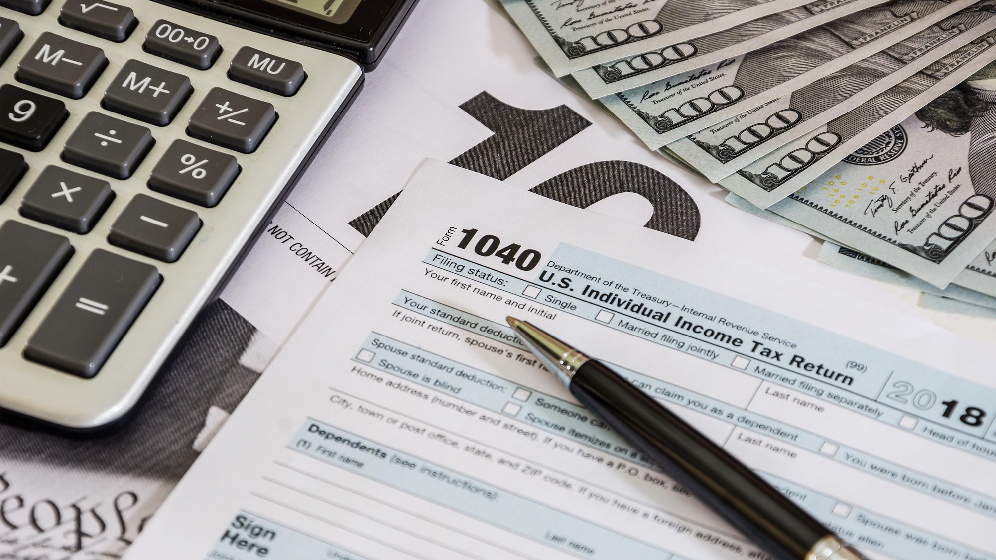 tax forms 1040 and calculator with dollars