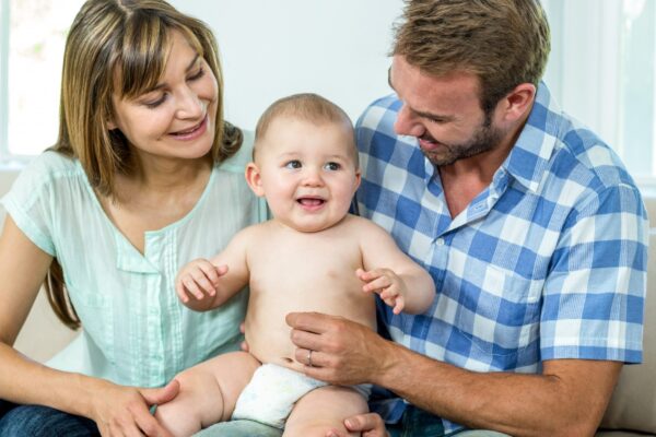 Parents playing with cute baby boy on sofa