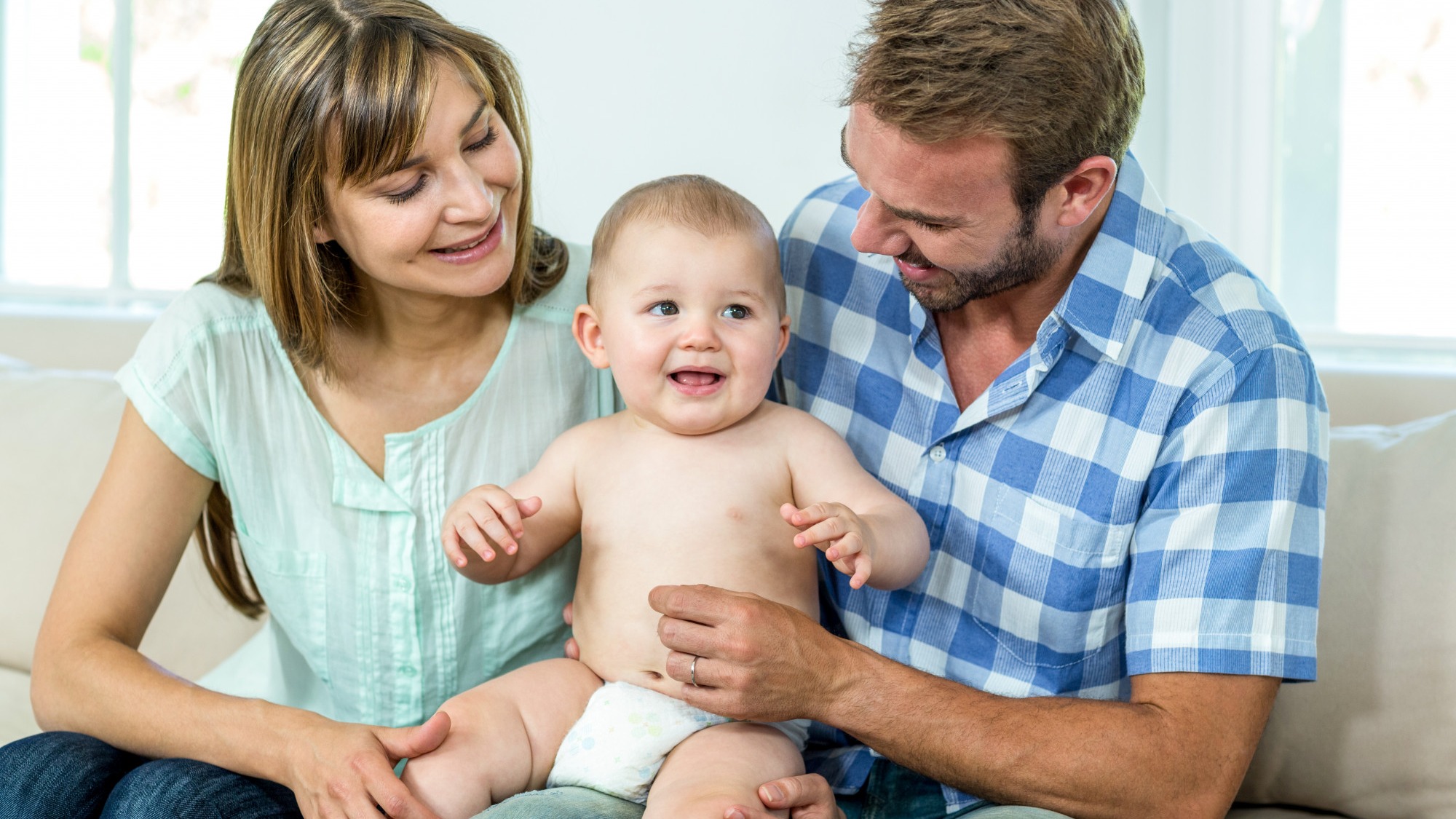 Parents playing with cute baby boy on sofa