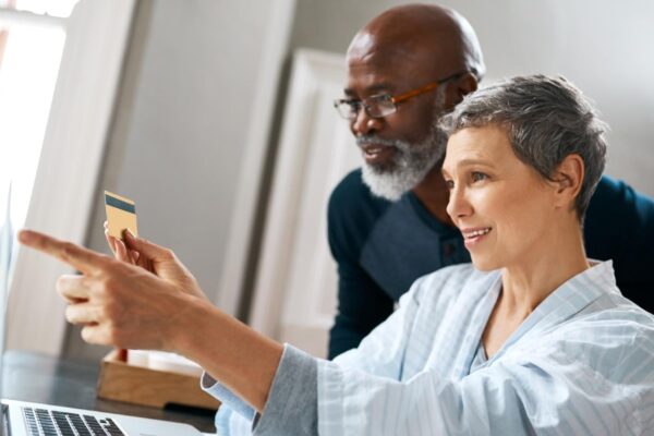 Laptop online shopping and retirement with senior interracial couple in home together for bank payment Computer credit card or ecommerce with happy man and woman in apartment for internet purchase
