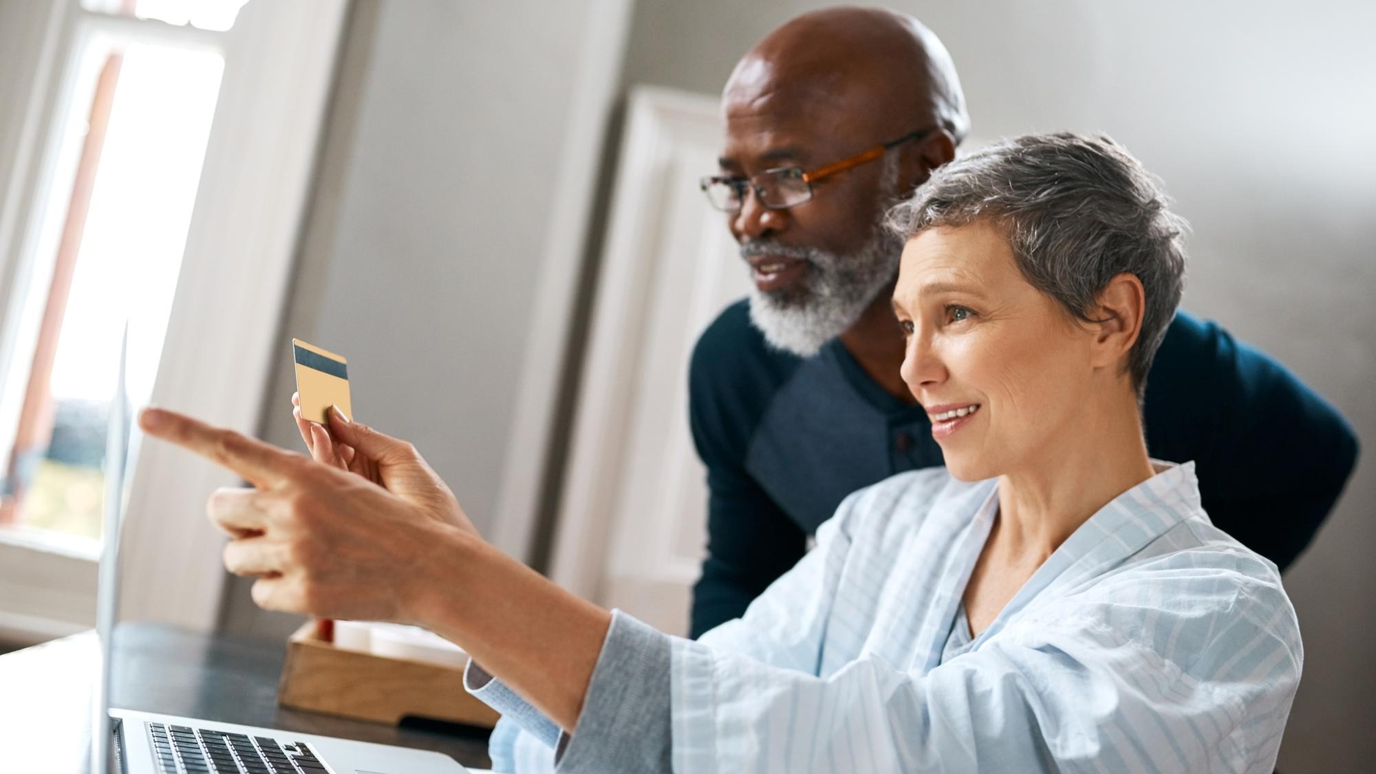 Laptop online shopping and retirement with senior interracial couple in home together for bank payment Computer credit card or ecommerce with happy man and woman in apartment for internet purchase