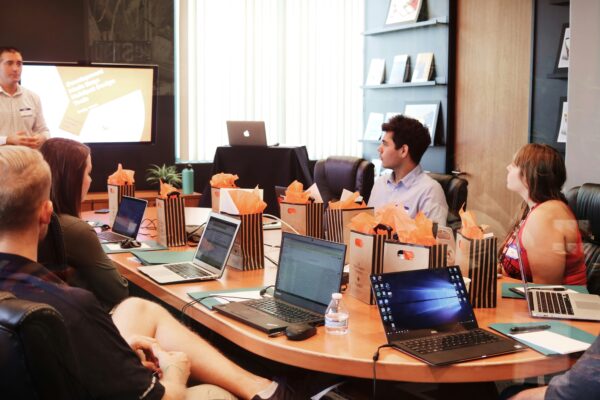 man standing in front of people sitting beside table with laptop computers