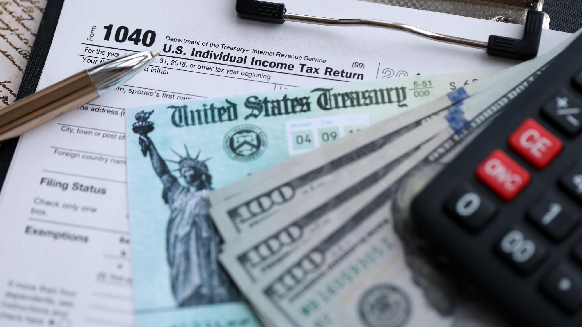 United States 1040 tax form individual income tax return with refund check and US dollar bills