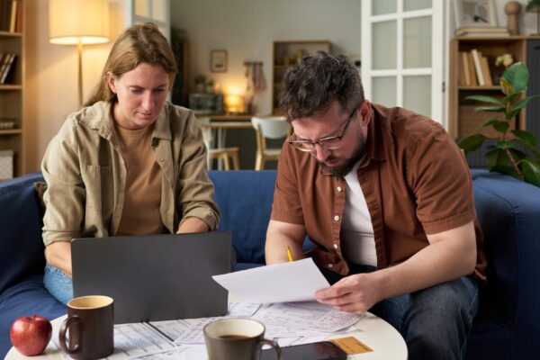 Caucasian young adult man and woman reviewing financial papers while paying taxes
