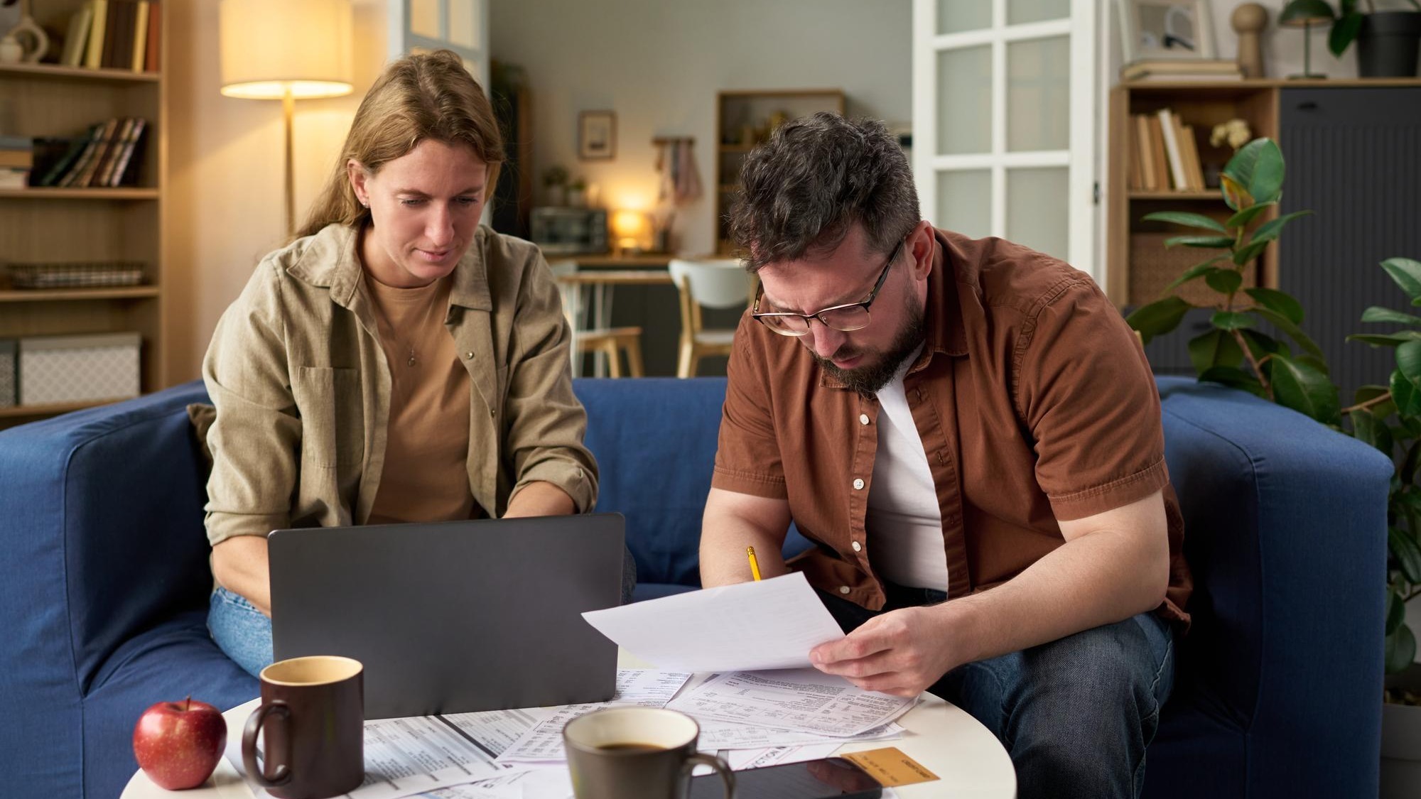 Caucasian young adult man and woman reviewing financial papers while paying taxes