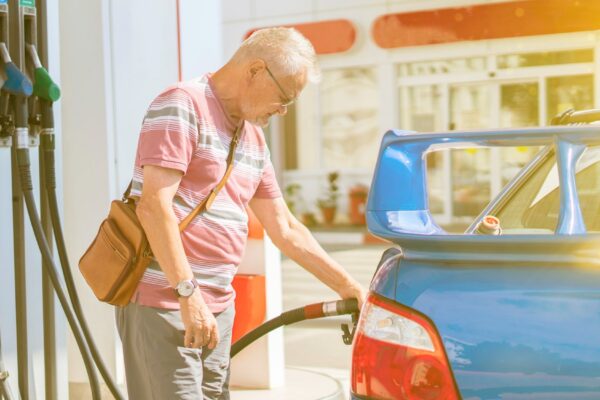 The old senior man refill his car with gasoline on the fuel station tourist traveling