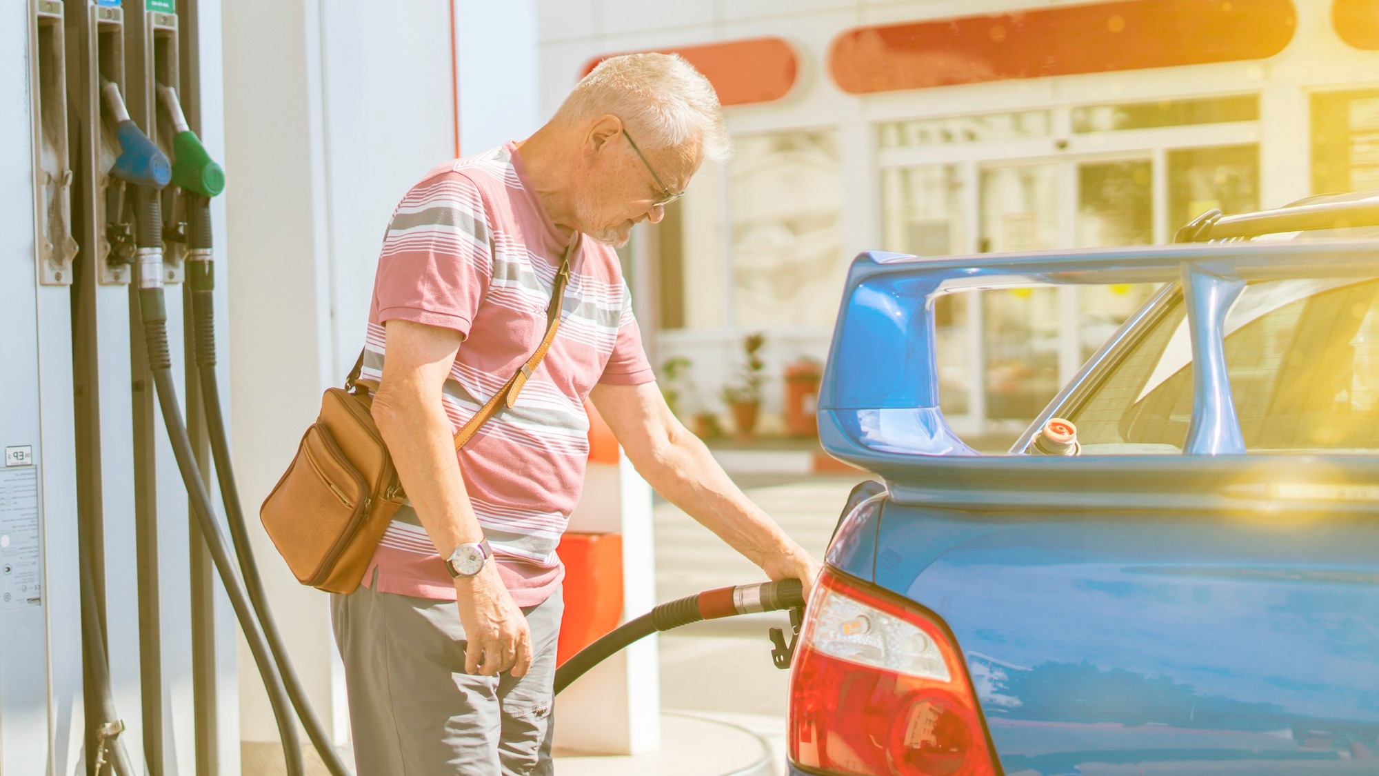 The old senior man refill his car with gasoline on the fuel station tourist traveling