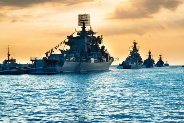 Military navy ships in a sea bay at sunset time