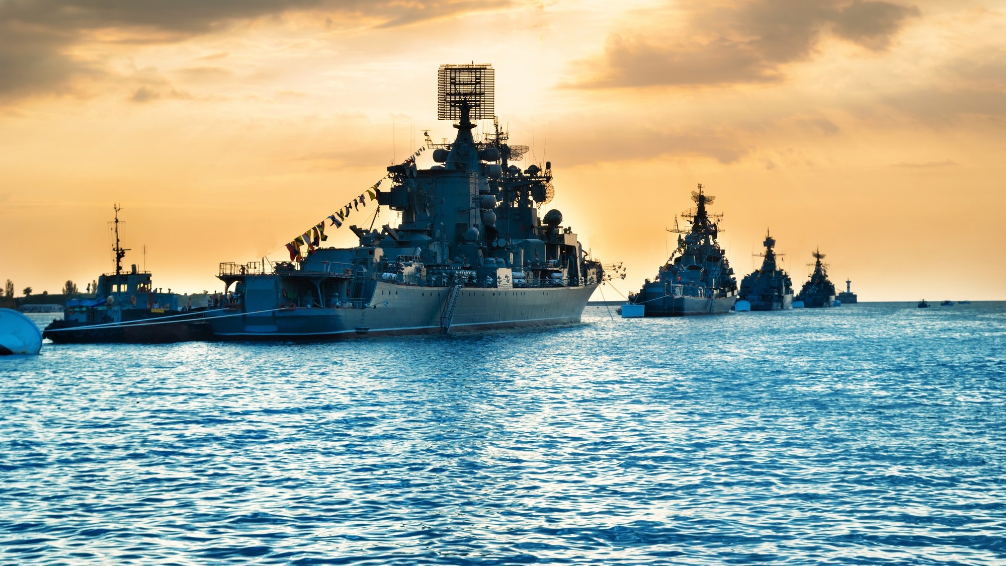 Military navy ships in a sea bay at sunset time
