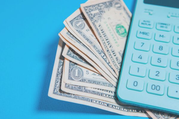 Us dollar bills and a calculator on blue background