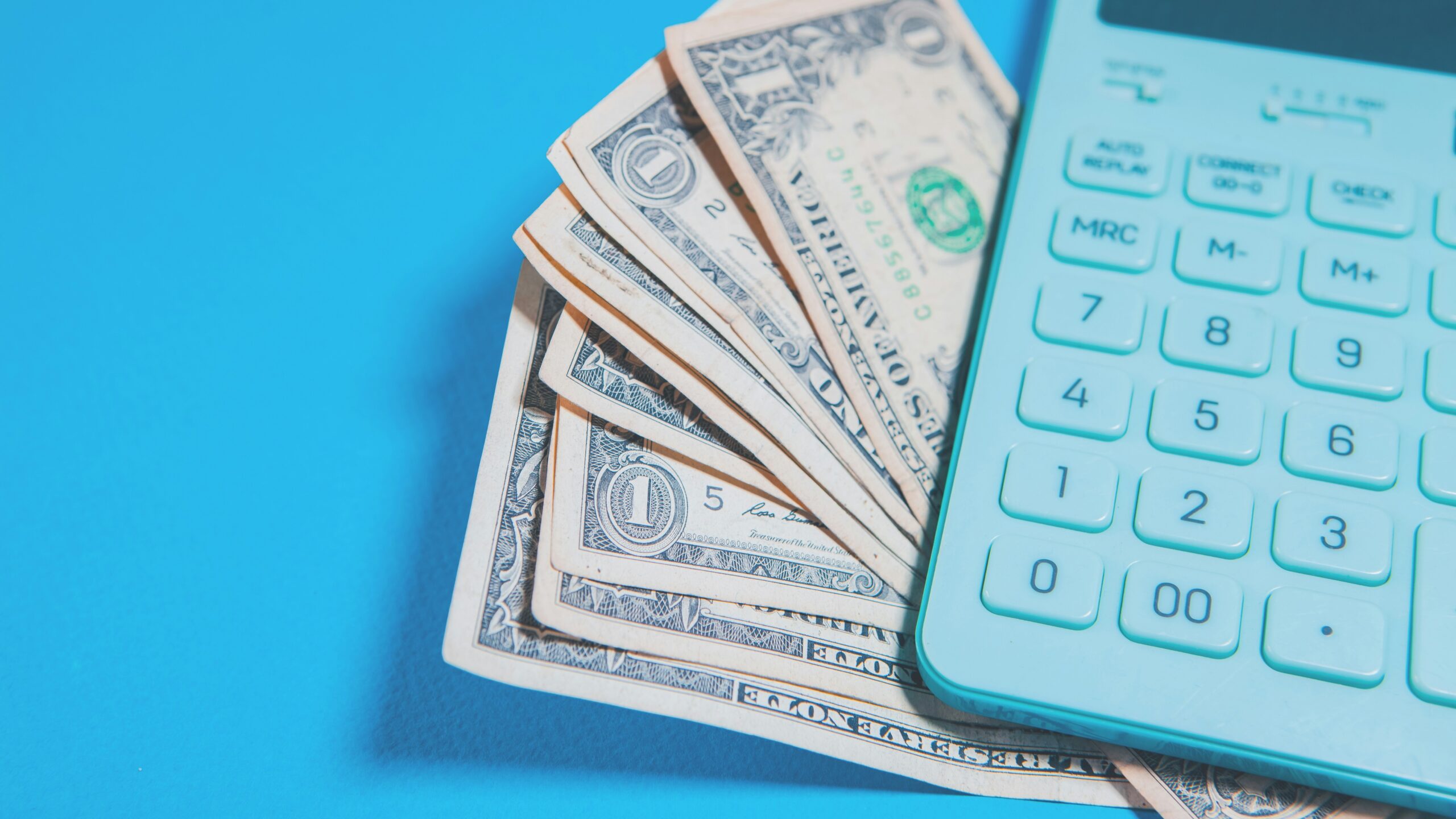 Us dollar bills and a calculator on blue background