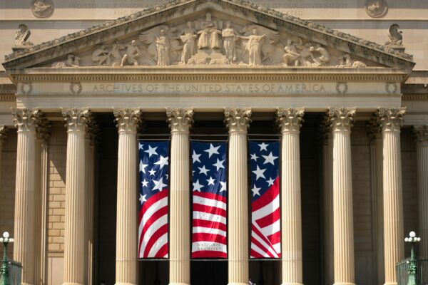 a building with columns and two american flags on it