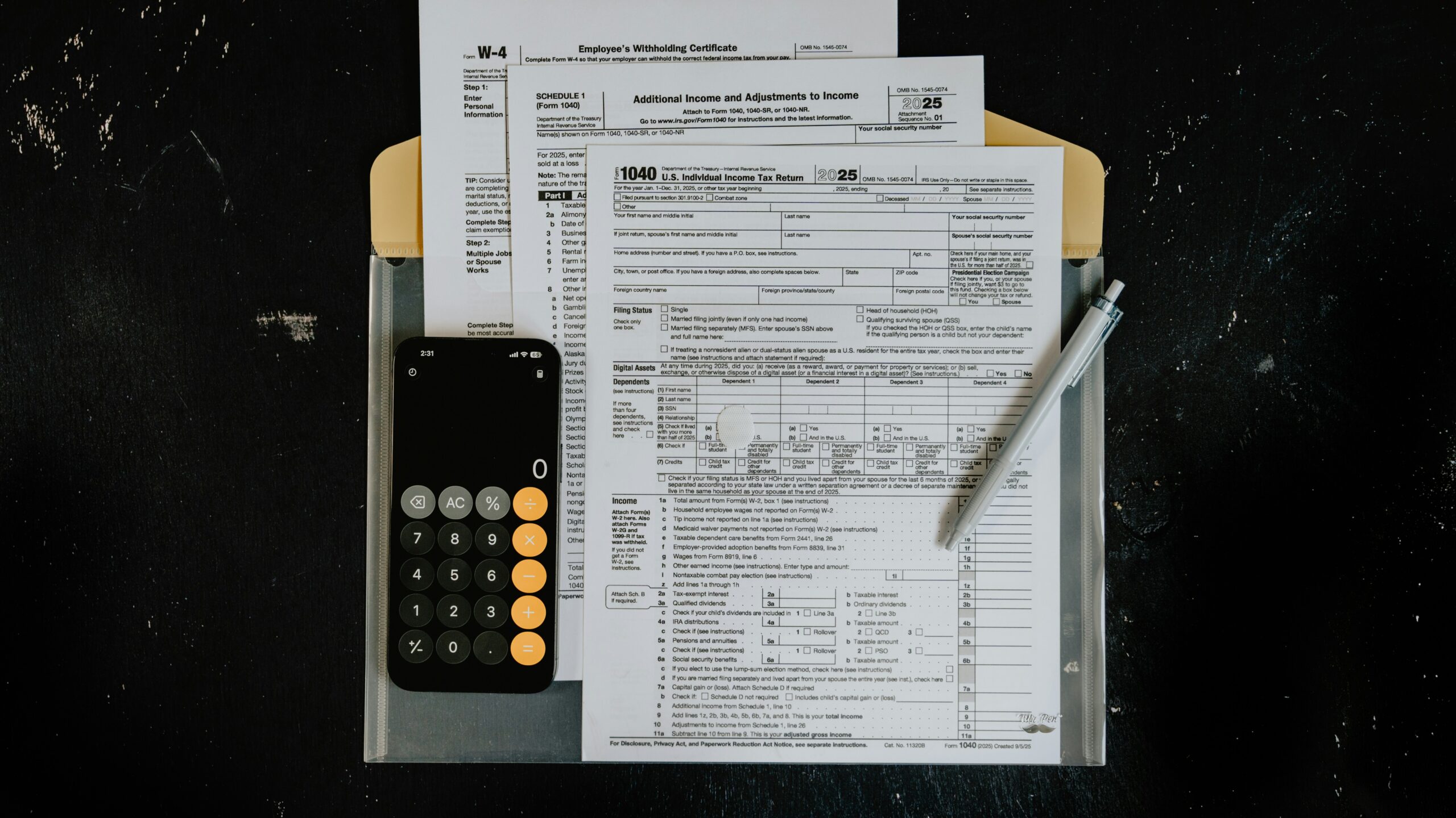 Tax forms with calculator and pen on dark surface