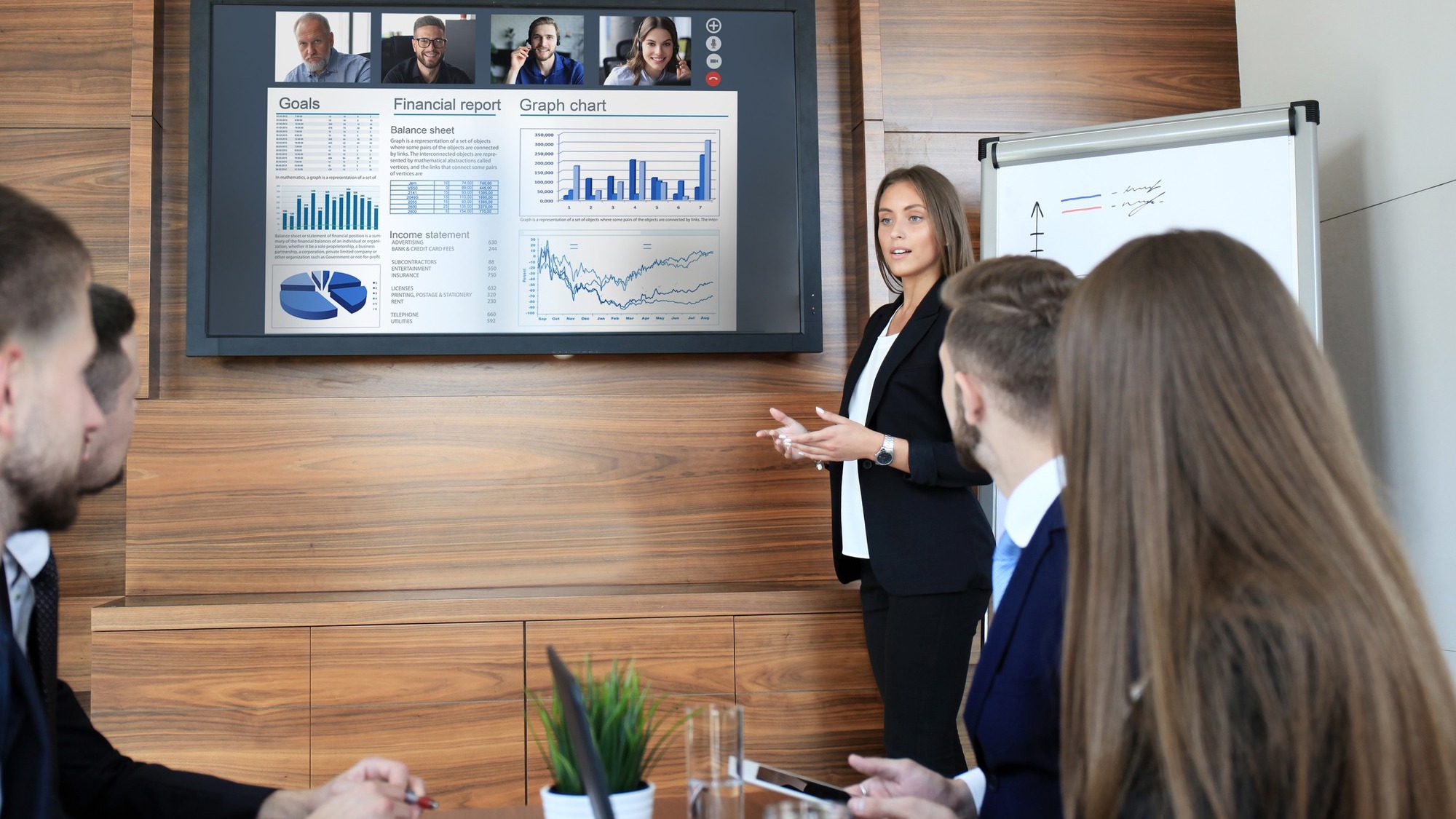 Business team at office, businessman presenting and discussing successful financial report of their company, on screen of plasma TV at meeting room, talking to his colleagues in video conference.