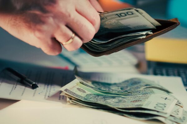 Hands counting money from a wallet over papers.