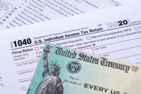 US Treasury stimulus check laying on a form 1040 tax return for 2020 to illustrate questions about qualification for payment