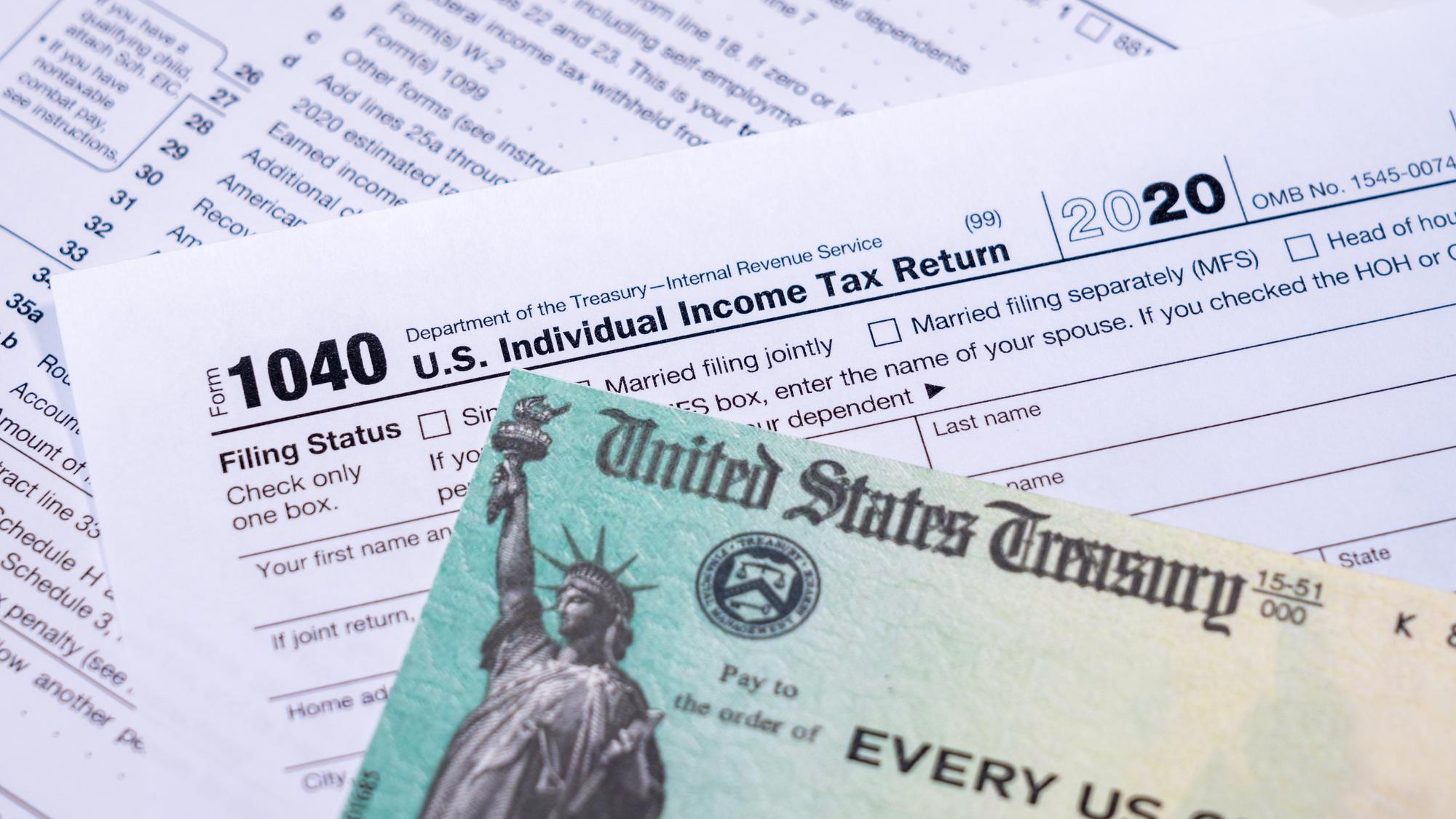 US Treasury stimulus check laying on a form 1040 tax return for 2020 to illustrate questions about qualification for payment