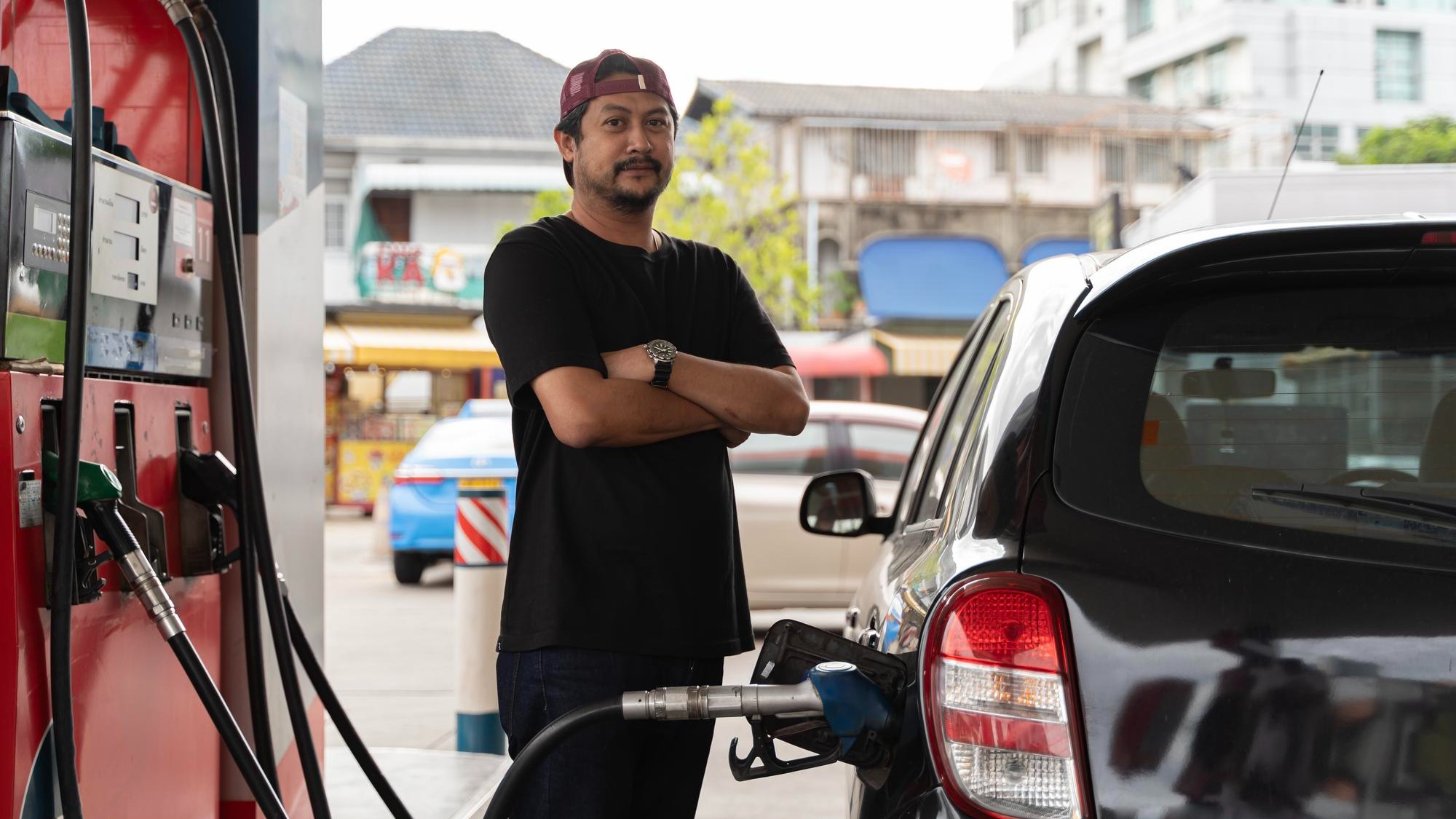 Portrait of a smiling businessman refueling his luxury car at the gas station Man driver hand refilling and pumping gasoline oil the car with fuel at he refuel station