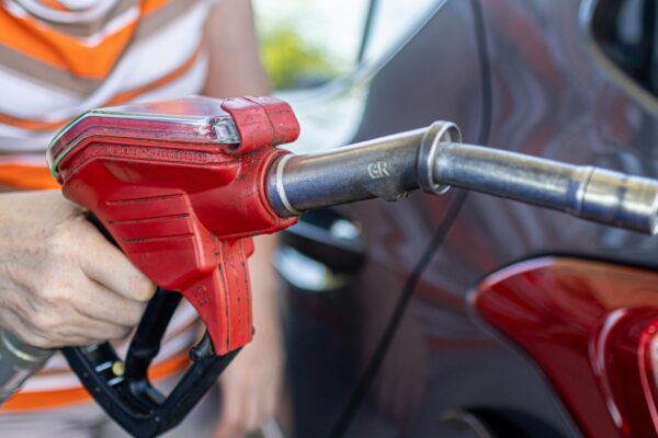 a woman filling a car with gas at a gas station