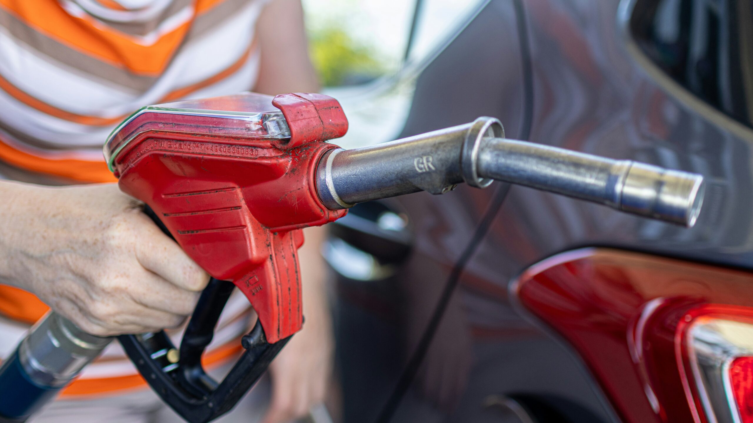 a woman filling a car with gas at a gas station