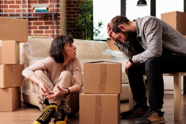 Frustrated married couple fighting in new apartment flat, moving in household property and having argument. Arguing and being in conflict over furniture decorations, relocation life event.