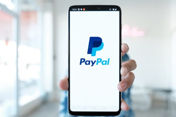 Woman hands holding smartphone with PayPal apps on the screen. PayPal is an online electronic payment system.