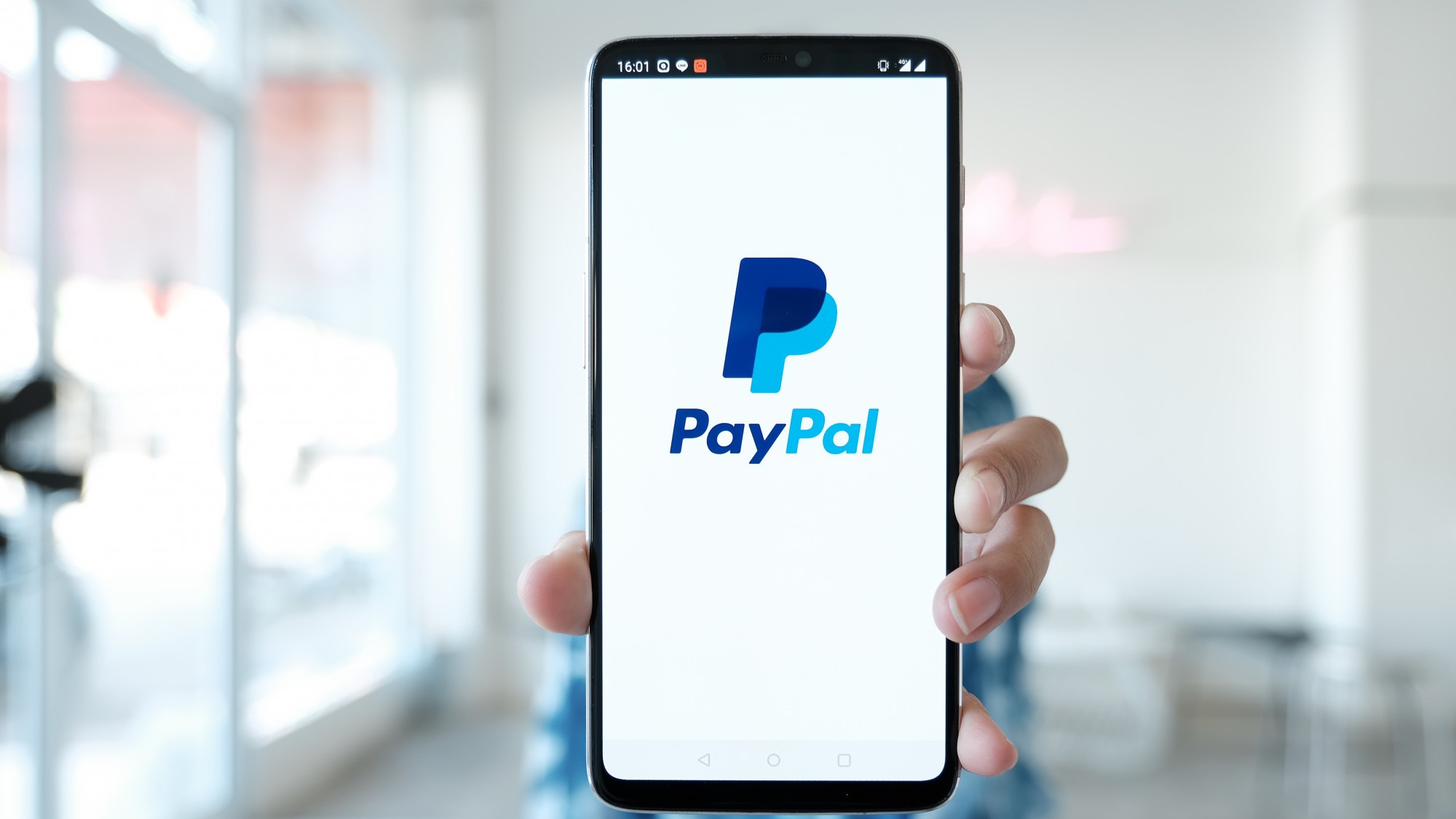 Woman hands holding smartphone with PayPal apps on the screen. PayPal is an online electronic payment system.