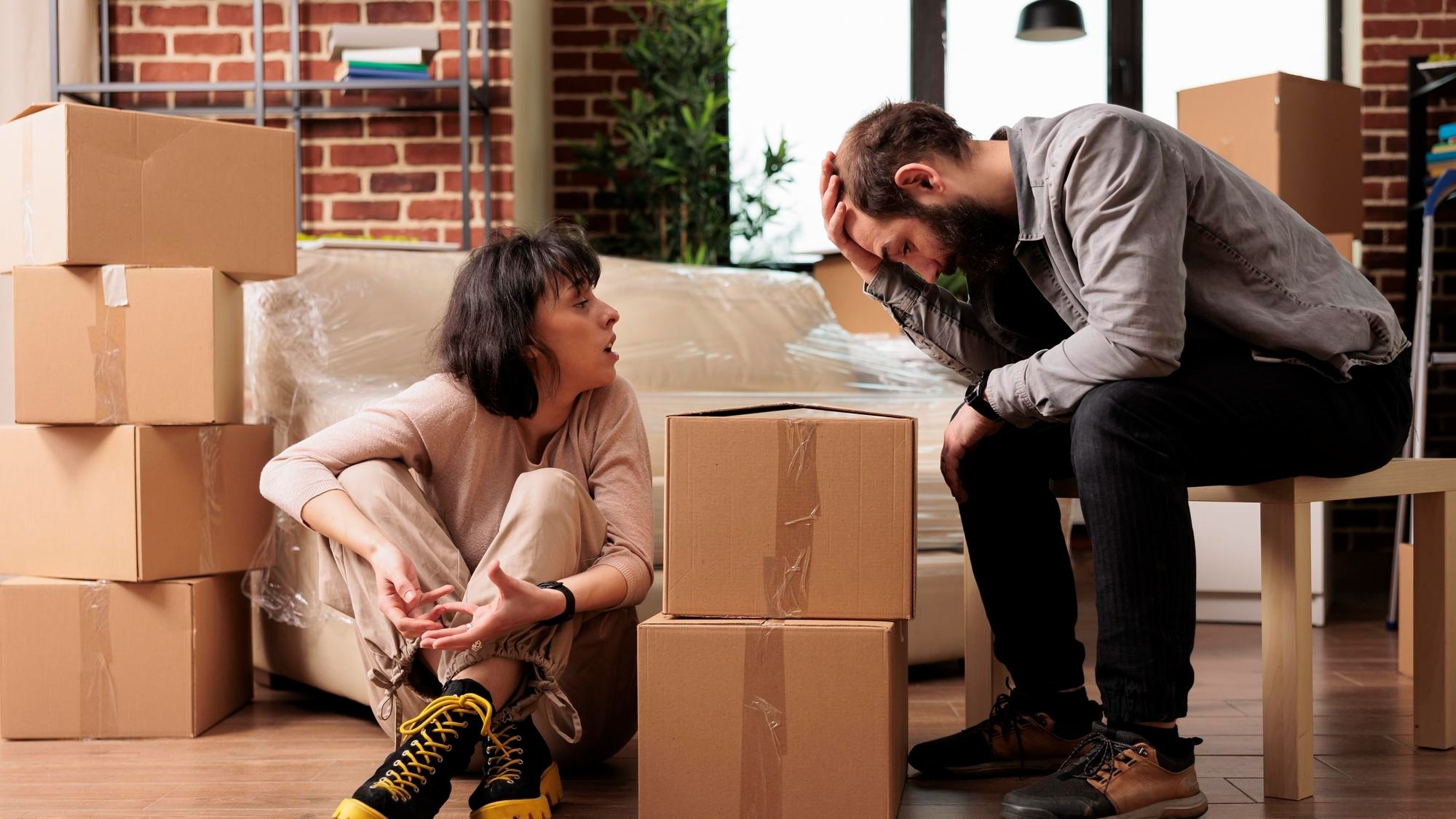 Frustrated married couple fighting in new apartment flat, moving in household property and having argument. Arguing and being in conflict over furniture decorations, relocation life event.