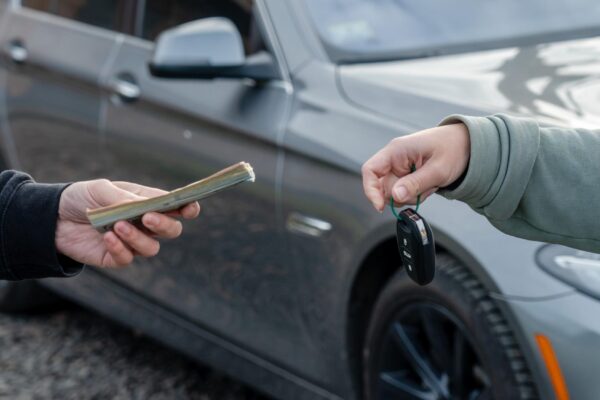 Deal of buying or renting car concept Hand with car keys other hand gives money