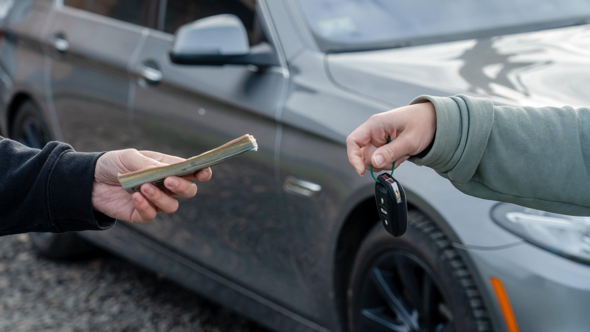 Deal of buying or renting car concept Hand with car keys other hand gives money