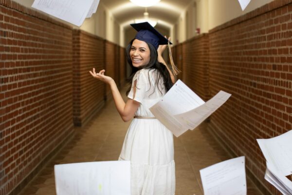 a woman in a graduation cap throwing papers in the air
