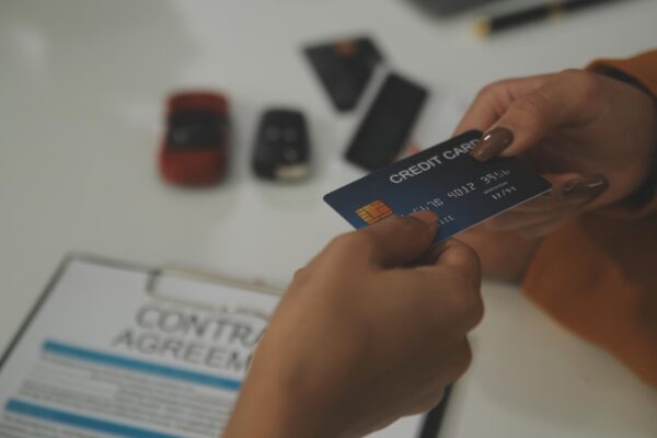 auto business sale and people concept close up of customer giving credit card to car dealer in auto show or salon