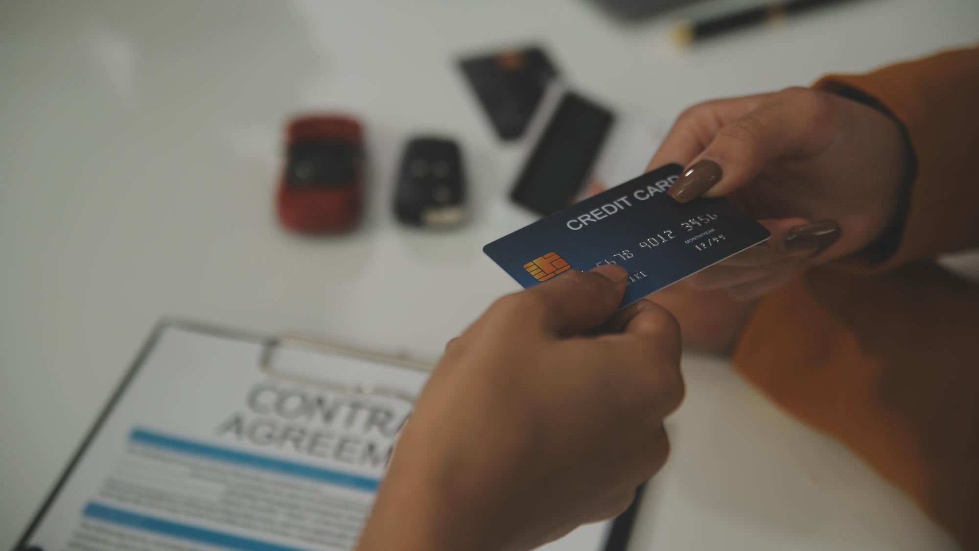 auto business sale and people concept close up of customer giving credit card to car dealer in auto show or salon